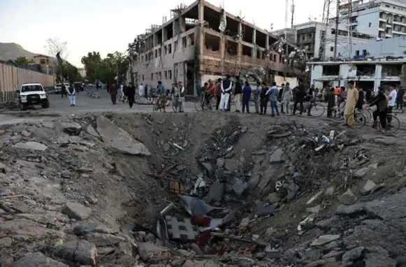  ?? WAKIL KOHSAR/AFP/GETTY IMAGES ?? Afghan security forces and residents inspect the crater left by a suicide truck bomb in Kabul, which killed dozens and injured hundreds. The blast was 300 metres from the Canadian Embassy.