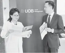  ??  ?? Lim (le ) and Wellington Management Singapore Pte Ltd investment specialist Brian Yeong look on at a brochure detailling the United Global Healthcare Fund yesterday.