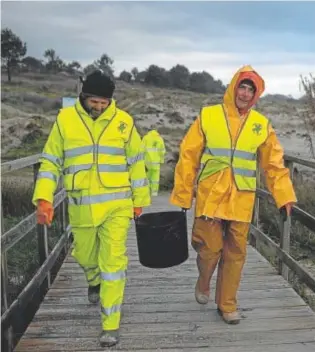  ?? // EP ?? Dos hombres cargan un cubo de pélets, en enero, en Queiruga (La Coruña)