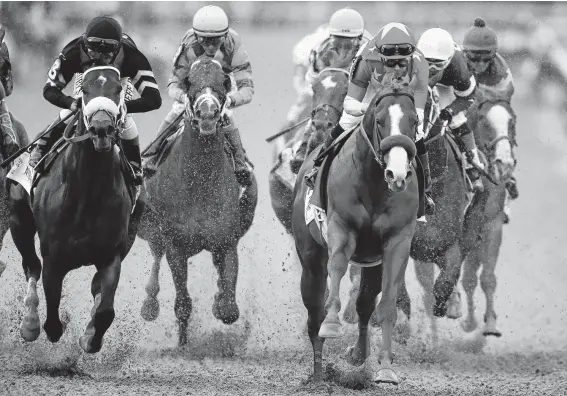  ?? Andres Kudacki / Associated Press ?? Justify, right foreground, with jockey Mike Smith up, leads the pack as it approaches the first turn during the 150th running of the Belmont Stakes on Saturday.