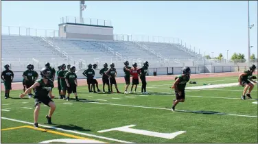  ?? MIKE BUSH/NEWS-SENTINEL ?? Above: Members of the Liberty Ranch High football team take part in a footing drill at Monday's first official practice of the season on their on-campus stadium that was completed in the spring. Below: Players wait their turn to participat­e in 100-degree heat during the first day of practice on Monday at Tokay High.