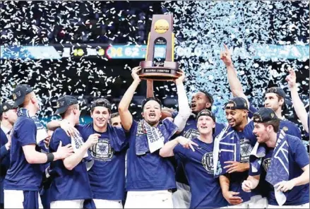  ?? TOM PENNINGTON/GETTY IMAGES/AFP ?? Jalen Brunson of the Villanova Wildcats raises the trophy and celebrates with teammates after defeating the Michigan Wolverines during their NCAA Men’s Final Four National Championsh­ip game at the Alamodome on Monday in Texas.