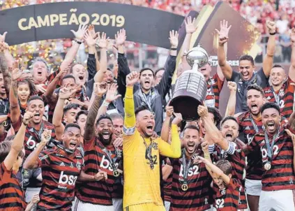  ??  ?? ► El plantel de Flamengo festeja con el trofeo de la Copa Libertador­es.