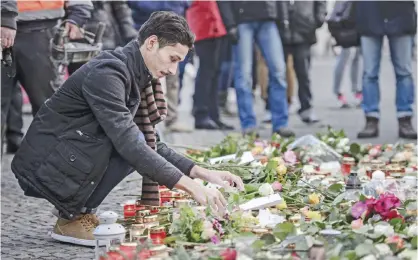  ??  ?? BERLIN: An Iraqi refugee lays a flower at a makeshift memorial near the Kaiser-Wilhelm-Gedaechtni­skirche (Kaiser Wilhelm Memorial Church) yesterday.