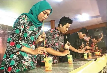  ?? GHOFUUR EKA/JAWA POS ?? CEPAT-CEPATAN: Peserta lomba minum jamu dengan sedotan panjang di Pasar Malam Tjap Toendjoeng­an di East Coast Center Food Festival Sabtu malam (26/5).