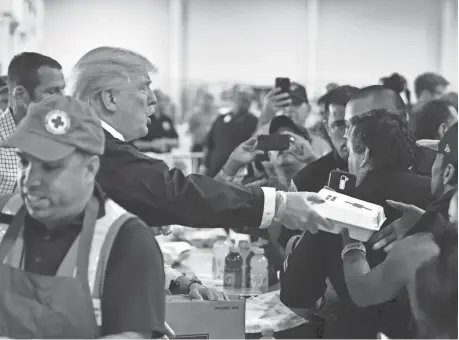  ?? NICHOLAS KAMM/AFP/GETTY IMAGES ?? President Donald Trump passes out hot dogs in Red Cross containers to Hurricane Harvey victims at NRG Center in Houston on Saturday.