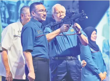  ??  ?? Najib checks out an automatic rifle while Hishammudd­in looks on. — Bernama photo