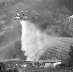  ??  ?? A fire department helicopter makes a water drop building on the vineyard estate of media mogul Rupert Murdoch in Bel Air, on the west side of Los Angeles, California. — Reuters photo