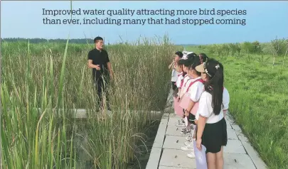  ?? ?? Han Zhanqiao (left) introduces wetland and bird conservati­on to a group of primary students at the lake.