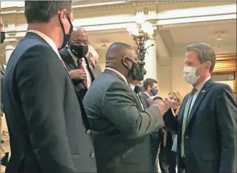  ?? Jeff Amy / AP/TownNews.com Content Exchange ?? Georgia Gov. Brian Kemp (right) bumps fists with Democratic state Rep. Carl Gilliard of Garden City on Tuesday, Feb. 16, 2021, at the state Capitol in Atlanta. The Republican Kemp announced a plan to abolish Georgia’s citizen’s arrest law, blamed in the 2020 shooting death of Ahmaud Arbery near Brunswick, Ga.