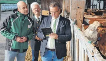  ?? FOTO: SYBILLE GLATZ ?? Uwe Eilers vom LAZBW in Aulendorf (von links) zeigt Landtagsab­geordneter Klaus Burger (CDU) und Landwirtsc­haftsminis­ter Peter Hauk (CDU) die Funktionsw­eise der neuen Tierwohl-app „PRO-Q-BW“.