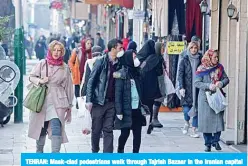  ??  ?? TEHRAN: Mask-clad pedestrian­s walk through Tajrish Bazaar in the Iranian capital Tehran. —AFP