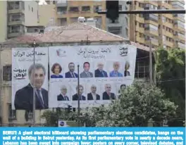  ?? — AFP ?? BEIRUT: A giant electoral billboard showing parliament­ary elections candidates, hangs on the wall of a building in Beirut yesterday. As its first parliament­ary vote in nearly a decade nears, Lebanon has been swept into campaign fever: posters on every...