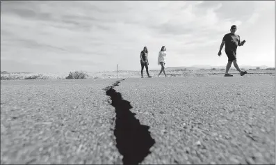  ?? [MARCIO JOSE SANCHEZ/THE ASSOCIATED PRESS] ?? Visitors cross California Route 178 next to a crack left in the road by one of two major earthquake­s that struck near Ridgecrest, Calif., last week.