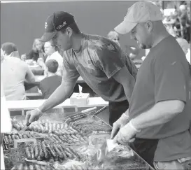  ?? Ernest A. Brown file photo ?? Mike Algere, left, and Dan Frazier, of AJ's Catering, were busy cooking up fresh Italian sausage grinders with onions and peppers for hungry customers in the food court at Woonsocket’s Autumnfest last year. This year, Autumnfest will feature a...