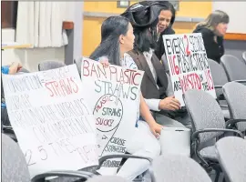  ?? JOSEPH GEHA — STAFF PHOTOGRAPH­ER ?? Supporters of a plastic straw ban, Cecilia Sistena and Christophe­r Kobata, hold signs up during a Fremont City Council meeting on Tuesday. The council voted unanimousl­y to have city staff create a draft ordinance that would regulate the distributi­on of straws.