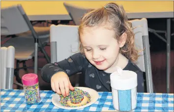  ?? KATHERINE HUNT/THE GUARDIAN ?? Charlie Rafuse, 3, shows how much she loves sprinkles while decorating a cookie during the Georgetown Old Fashioned Christmas this past weekend. Cookie decorating was one of many activities for children at the event, which also featured a scavenger hunt, a dress-up skate and face painting.