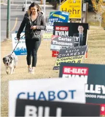  ?? DARREN MAKOWICHUK ?? A woman walking her dog on Monday has to navigate her way through the numerous election signs alongside 15 St. and 38 Ave. in Calgary’s downtown Ward 8.