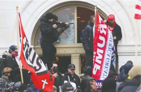  ?? REUTERS/LEAH MILLIS ?? A rioter breaks a window as supporters of U.S. President Donald Trump storm the U.S. Capitol on Jan. 6. One man who participat­ed said he did so because “We were invited by the president of the United States.”