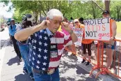  ?? JAE C. HONG/ASSOCIATED PRESS ?? A National Rifle Associatio­n member plugs his ears with his fingers as he walks past protesters during the NRA’s annual meeting in Houston on Friday.