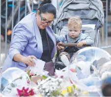  ?? Picture: Richard Dobson ?? Jelina Turnbull with her one-year-old son Liam visits the scene at Bondi Junction and reads floral tributes.