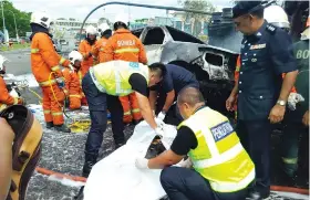  ??  ?? Police officers covering the charred remains of the tanker driver.