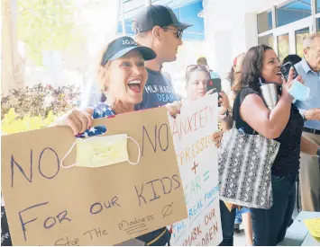  ?? MARTA LAVANDIER/AP ?? Joann Marcus of Fort Lauderdale, left, cheers as she listens to the Broward School Board’s emergency meeting Wednesday in Fort Lauderdale, Florida.