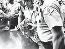  ?? CHICAGO TRIBUNE HISTORICAL PHOTO ?? Police hold an anti-war protester over the hood of a car in front of the Conrad Hilton in 1968 during the Democratic National Convention.