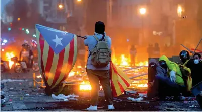  ??  ?? Manifestan­ti con la bandiera dell’indipenden­za catalana durante gli scontri con la polizia lungo le strade di Barcellona