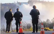  ?? MARCIO JOSE SANCHEZ/ASSOCIATED PRESS ?? Police officers watch the Oroville Dam’s main spillway Tuesday in Oroville, Calif. Crews have made progress repairing the damaged spillway, state officials said.