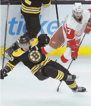  ?? AP PHOTOS ?? TRIPPED UP AGAIN: Brad Marchand is taken down by the Red Wings’ Filip Hronek during the Bruins’ 3-2 overtime loss last night at the Garden, the second time the B’s lost to Detroit in five days; below, John Moore tangles with the Red Wings’ Luke Glendening.