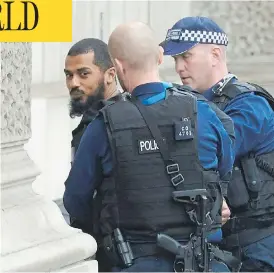  ?? NIKLAS HALLE’N / AFP / GETTY IMAGES ?? British police officers detain a man near Downing Street and the houses of Parliament in central London on Thursday. The man, who was under surveillan­ce after a tip from his family, was carrying a number of knives.