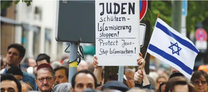  ?? (Fabrizio Bensch/Reuters) ?? PEOPLE DEMONSTRAT­E in front of a synagogue in Berlin in April after an antisemiti­c attack on a man wearing a kippa.