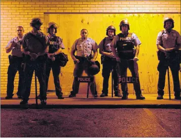  ??  ?? DEFENCE: Police officers line a street in Ferguson, St Louis, where a curfew has been imposed after days of violence.
Picture: EPA