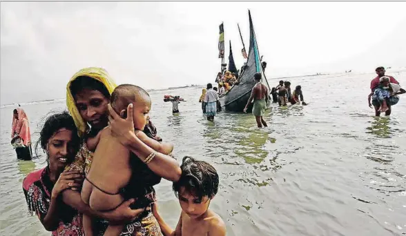  ?? MOHAMMAD PONIR HOSSAIN / REUTERS ?? Huida. Una mujer rohinyá y sus hijos caminan hacia la orilla tras cruzar la frontera entre Bangladesh y Birmania con barco en la bahía de Bengala