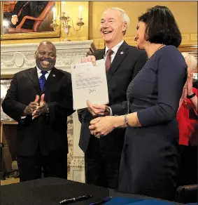  ?? Arkansas Democrat-Gazette/STATON BREIDENTHA­L ?? Centers for Medicare and Medicaid Services Administra­tor Seema Verma (right) makes a rare personal delivery to Gov. Asa Hutchinson (center) on Monday of a federal waiver allowing Arkansas to require participan­ts in the state’s expanded Medicaid program...