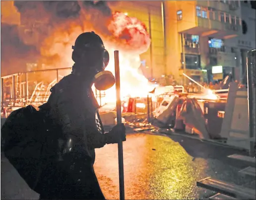  ??  ?? A protester looks on as barricades burn in Wan Chai, Hong Kong yesterday