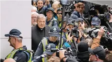  ?? FOTO: REUTERS ?? In Melbourne bahnte sich gestern George Pell, eskortiert von mehreren Polizisten, seinen Weg ins Gerichtsge­bäude.