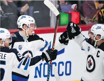  ?? PHOTOS: MARTTI KAINULAINE­N/LEHTIKUVA VIA AP ?? Patrik Laine, centre, celebrates a goal with Mark Scheifele, left, and Blake Wheeler Thursday during a 4-2 Jets win over Florida in Helsinki.