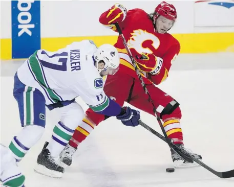  ?? Colleen De Neve/calgary Herald ?? Calgary Flames centre Max Reinhart battles to keep his balance while being checked by Vancouver Canucks centre Ryan Kesler Wednesday night.