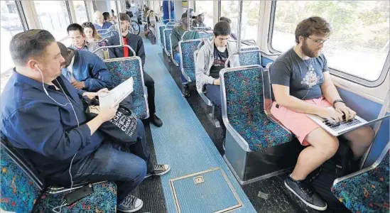  ?? Al Seib Los Angeles Times ?? JOSIAH DAVIS, right, rides the new Expo Line extension to his tech job in Santa Monica, having started from his home in Long Beach. “I’ve been waiting for this day,” he said of the route’s opening last week. Commuting from Santa Monica to downtown by...