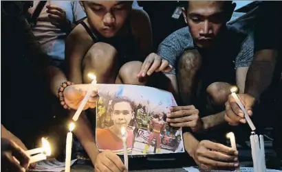  ?? AARON FAVILA / AP ?? Jóvenes filipinos iluminan con velas una imagen del joven asesinado por la policía en Manila el 2017