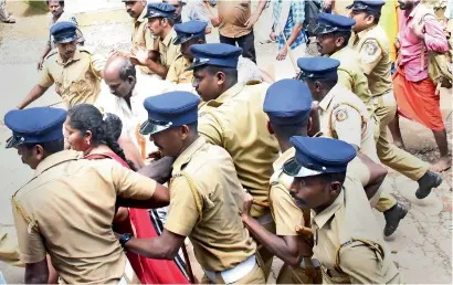  ?? PTI ?? Police escort Madhavi and her family members as she was heckled by the protesters after she tried to enter the Sabarimala temple. —