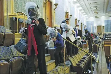  ?? Andrew Harnik Associated Press ?? MEMBERS OF Congress, wearing emergency gas masks, evacuate from the House gallery on Jan. 6, 2021. In the poll, 86% of Democrats but only 10% of Republican­s said Donald Trump should be charged with a crime.