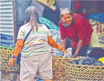  ?? MACKY LIM ?? SMILE. A vendor beams upon seeing the camera while packing charcoal for a customer, not minding that her face is covered with soot yesterday morning at Bankerohan Public Market.