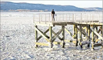  ??  ?? A man stands on a waterfront deck near the frozen Hudson River in Dobbs Ferry, New York. — AFP photo