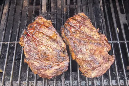  ?? RICARDO DEARATANHA/ LOS ANGELES TIMES ?? Simply prepared with a brush of mayonnaise and seasoned with salt and pepper, rib-eye steaks come off the grill juicy and mouth-watering.