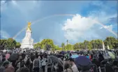  ?? Frank Augstein The Associated Press ?? People gather outside Buckingham Palace in London as a double rainbow appears in the sky on Thursday.