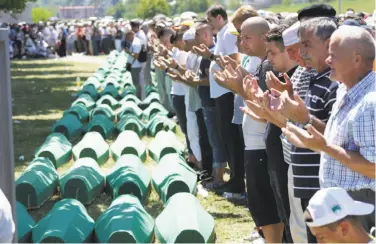  ?? Amel Emric / Associated Press ?? Bosnian Muslims pray in front of coffins during a ceremony for newly identified victims of the massacre.