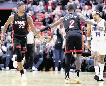  ?? AL DIAZ adiaz@miamiheral­d.com ?? Heat forward Jimmy Butler (22) and guard Terry Rozier celebrate after Butler sinks a three-pointer against the Magic on Tuesday at Kaseya Center in Miami. The Heat traded for Rozier two weeks ago but stood pat on Thursday.
